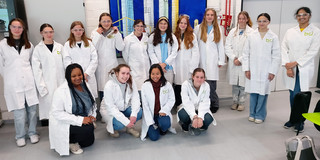 Gruppenfoto der Nachmittagsgruppe MinTU, die Schülerinnen tragen Laborkittel und Schutzbrillen.