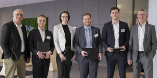 4 award winners hold their certificates, including Colin Johnson. To their left is Prof. Beyer, Rector of TU Dortmund University, and to their right is Mr. Baranowski, Chairman of the Society of Friends of TU Dortmund University. 