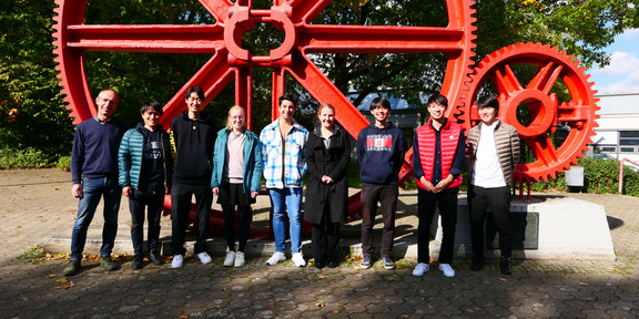 Gruppenfoto vom Japanpraktikum vor roten Zahnrädern