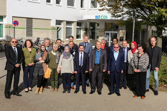 Eine Gruppe von Frauen und Männern stehen draussen vor einem Gebäude in zwei Reihen nebeneinander