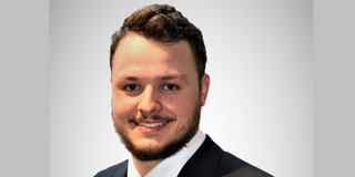 Portraitfoto von Michael-David Fischer. Er trägt einen Anzug mit farbiger Krawatte, hat dunkles, kurzes Haar und ist geschätzt Mitte 20.