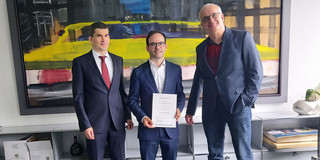 Prof. Lucia präsentiert seine Urkunde, rechts von ihm steht der Prodekan Lehre & Studium, Prof. Nett und links von ihm steht der Rektor, Prof. Bayer, 
