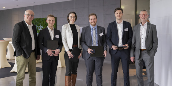 4 award winners hold their certificates, including Colin Johnson. To their left is Prof. Beyer, Rector of TU Dortmund University, and to their right is Mr. Baranowski, Chairman of the Society of Friends of TU Dortmund University. 
