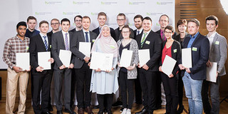Siebzehn Personen stehen zu einem Gruppenbild nebeneinader und halten ihre Urkunden in der Hand