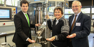 Tablettier-Workshop am Lehrstuhl von Prof. Thommes Eine Frau und zwei Männer stehen nebeneinander vor einer Tabletten-Maschine