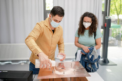 Student führt Versuch durch. Besucherin schaut zu.