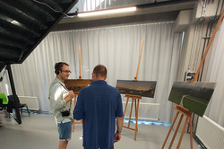 Maik Hester erklärt einem Besucher ein Exponat, bestehend aus 3 Bildern mit Soundinstallation 
