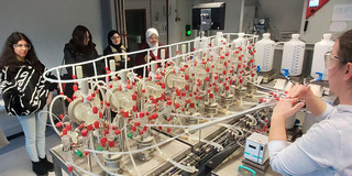 An employee explains the processes in a test facility to a group of students in the laboratory