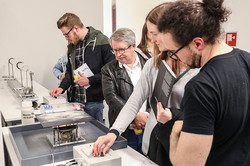 Besucher bei Ausstellung „Engineering meets Art“ schauen sich ein Objekt an
