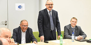 Besuch in Lodz Drei Personen: zwei sitzen an einem Tisch, eine Person in der Mitte steht