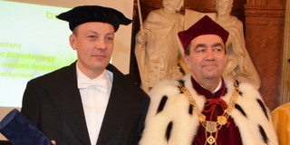 Zwei Männer mit historischen Universitäts-Gewändern stehen nebeneinander