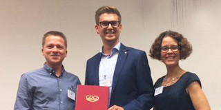 Dr. Thomas Seidensticker erhält Promotionspreis 2018 Drei Personen stehen nebeneinader in einem Raum. Mann in der Mitte hält eine Auszeichnung in der Hand