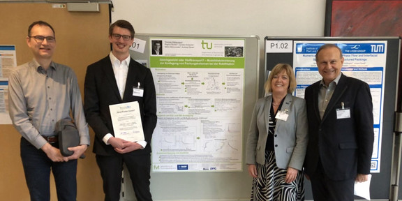 Vier Personen stehen vor einer Posterwand