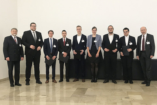 Neun Personen stehen nebeneinander in einem Raum vor einer weissen Wand