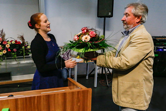 Eine Frau überreicht einem Mann einen bunten Blumenstrauss