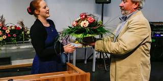 Eine Frau überreicht einem Mann einen bunten Blumenstrauss