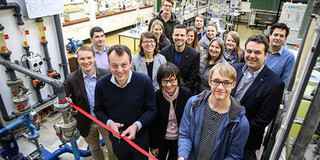 Praktikum 2.0 Gruppe von Frauen und Männer, ein Mann schneidet ein rotes Band mit einer Schere durch