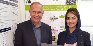 Posterpreis für Hina Qammar Ein Mann und eine Frau stehen vor einer Postwand. Die Frau hat eine Urkunde in der Hand