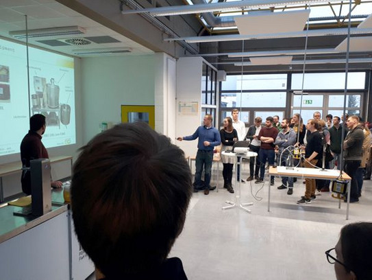 Brau AG stellt ihre Biere vor Personen stehen in einem Seminarraum und schauen auf eine Beamerwand, wo eine Präsentation läuft