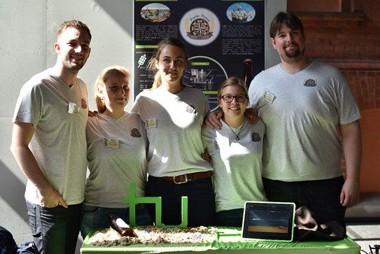 Drei Frauen und zwei Männer in weissen T-Shirts mit Logo stehen nebeneinander in einem Raum