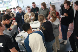 Studierende stehen gesammelt um Stehtische und reden mit Alumni