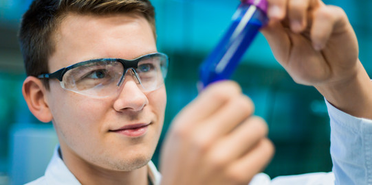 Eine forschende Person hält ein Probengefäß in der Hand.