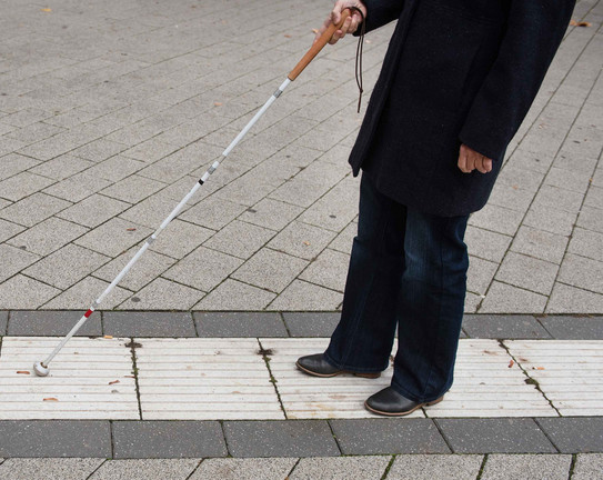 A blind person follows the guidance system for blind people on campus with the help of a blindman's stick.