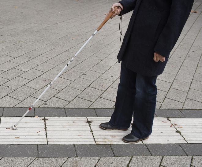 A blind person follows the guidance system for blind people on campus with the help of a blindman's stick.